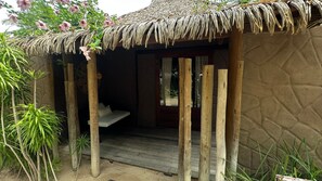 A thatched-roof hut with a wooden bench inside. - Aloha Village Hotel (Amontada)
