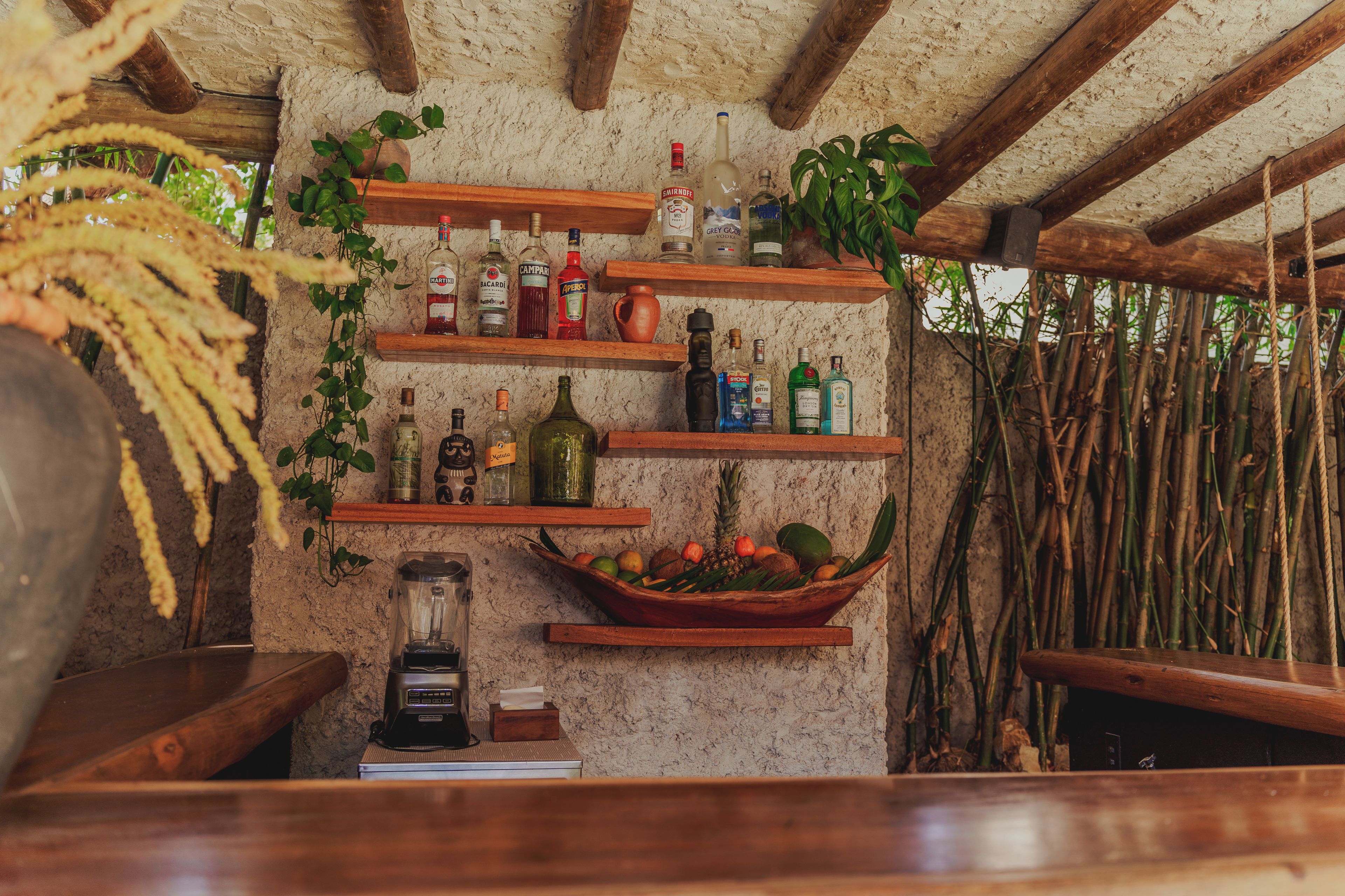 Eine rustikale Bar mit Holzböden und Regalen, die mit Flaschen und einer Obstschale bestückt sind.