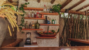 Eine rustikale Bar mit Holzböden und Regalen, die mit Flaschen und einer Obstschale bestückt sind.