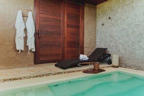 A pool area with a lounge chair, a bucket, and towels against a wooden door. - Aloha Village Hotel (Amontada)