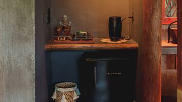 Cocina compacta con refrigerador, cafetera y repisa con una olla.