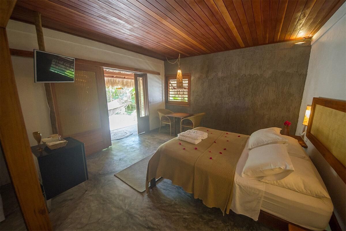 A room with a bed, a small table, a TV, and a window with a view of greenery.