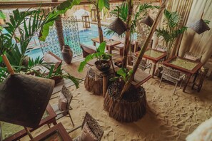 A tropical-themed indoor space with a pool, wicker furniture, and lush greenery. - Aloha Village Hotel (Amontada)