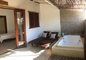 A room with a bed, a wooden bench, and a bathtub. - Aloha Village Hotel (Amontada)