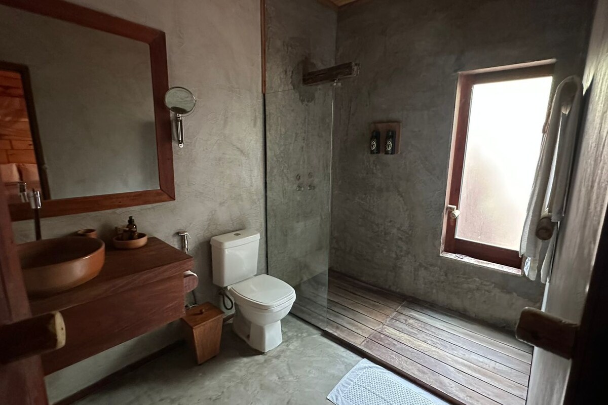 A bathroom with a wooden vanity, a white toilet, and a shower area.