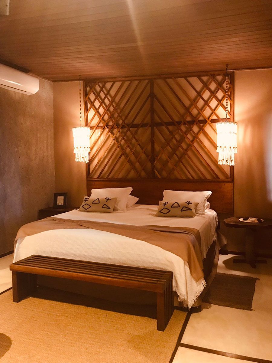Un dormitorio con cabecera de madera, una cama grande, dos mesitas de noche y dos lámparas de pared.