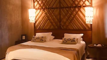 Un dormitorio con cabecera de madera, una cama grande, dos mesitas de noche y dos lámparas de pared.