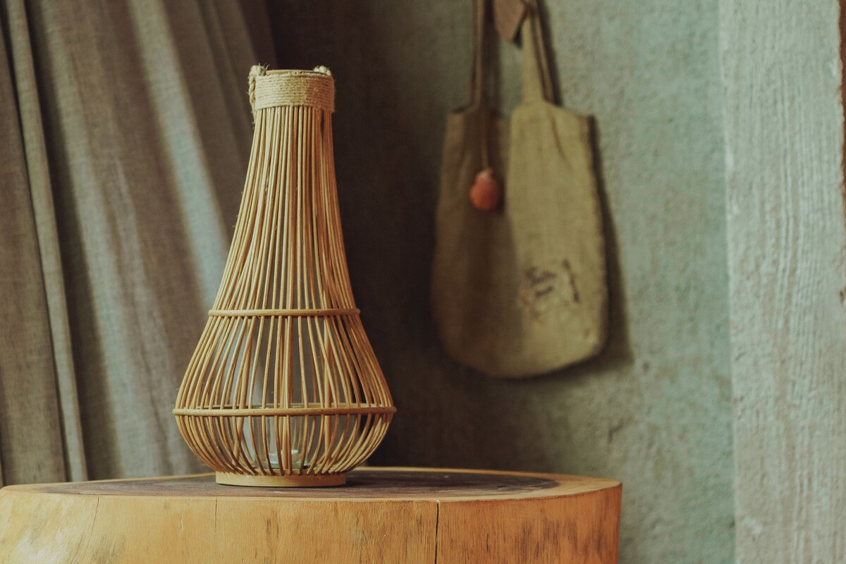 A round wooden table with a woven vase and two woven baskets on it.