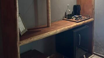 Een kamer met een houten bureau, een aan de muur bevestigde televisie, een klein krukje en een mand.
