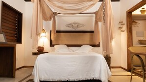 A bedroom with a canopy bed, a bedside lamp, a wooden headboard, and a patterned rug. - Aloha Village Hotel (Amontada)
