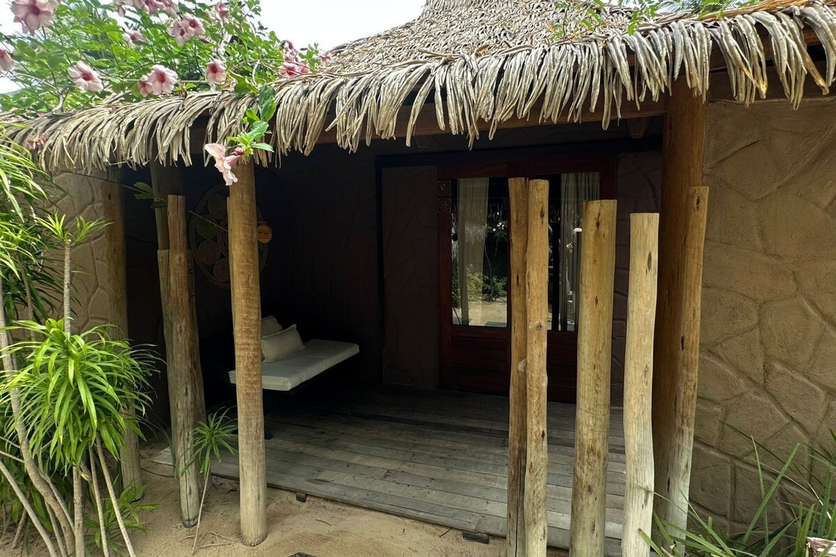 A thatched-roof hut with a wooden bench inside.