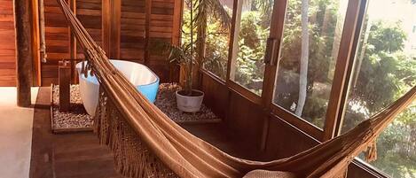 Un hamac dans une cabane en bois, avec vue sur la verdure environnante.