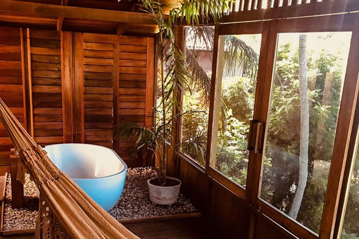 A hammock in a wooden room with a view of greenery outside.
