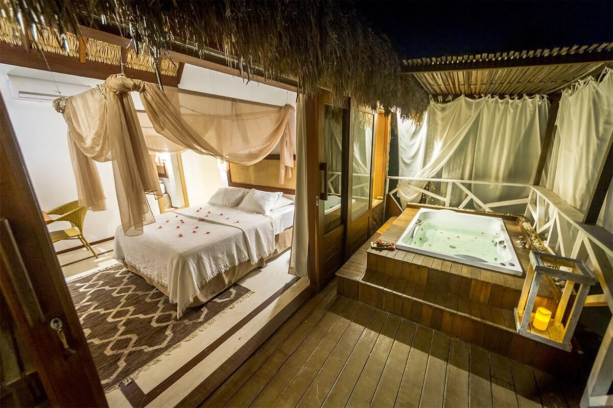 Quarto com cama de dossel, área de estar com vista e banheira de hidromassagem.