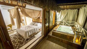 Quarto com cama de dossel, área de estar com vista e banheira de hidromassagem.