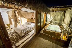 A bedroom with a canopy bed, a sitting area with a view, and a hot tub. - Aloha Village Hotel (Amontada)