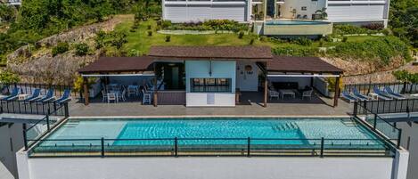 Relax by the rooftop pool surrounded by lush greenery and a hilly backdrop.