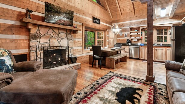 A cozy cabin interior with a fireplace, wooden walls, a dining area, and a kitchen. - FreeDollywood Tix/Secluded/Pool Table/Spacious (Gatlinburg)