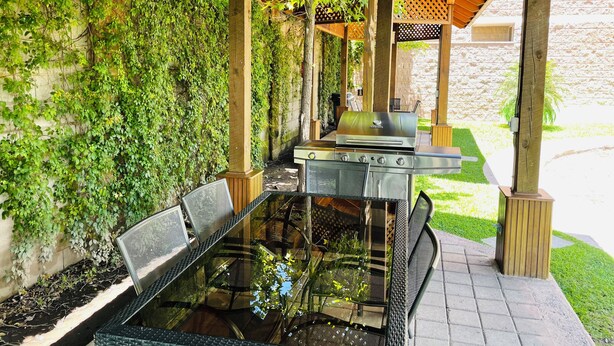 An outdoor patio with a glass-top table, metal chairs, and a stainless steel grill. - Beautiful private apartment Ecovivienda Etapa 1 (8 minutes American Embassy) (Tegucigalpa)