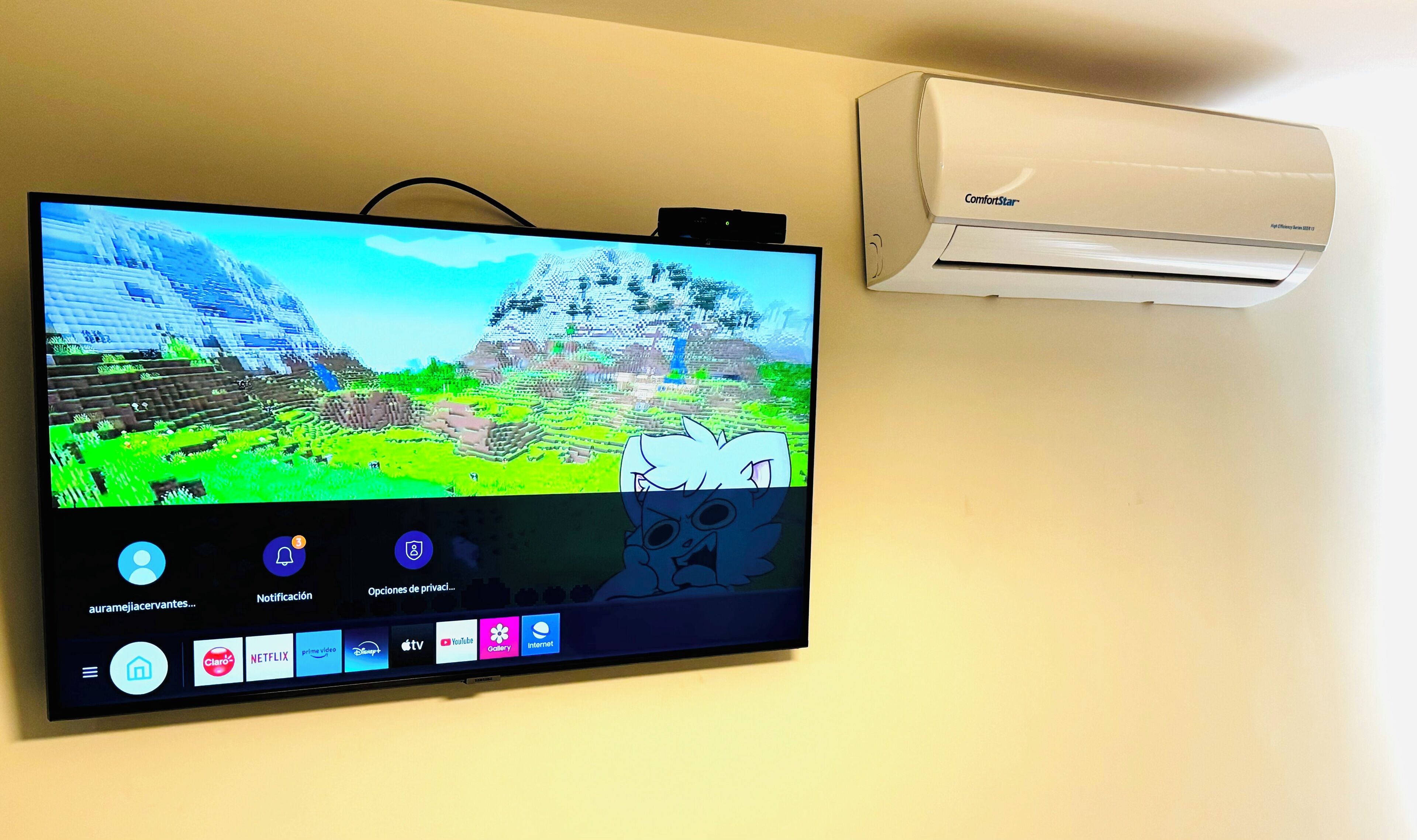 A flat-screen TV mounted on a wall with a white air conditioning unit beside it.