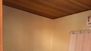 Una cama bien hecha con un cabecero marrón, una colcha blanca y una toalla doblada sobre la cama.