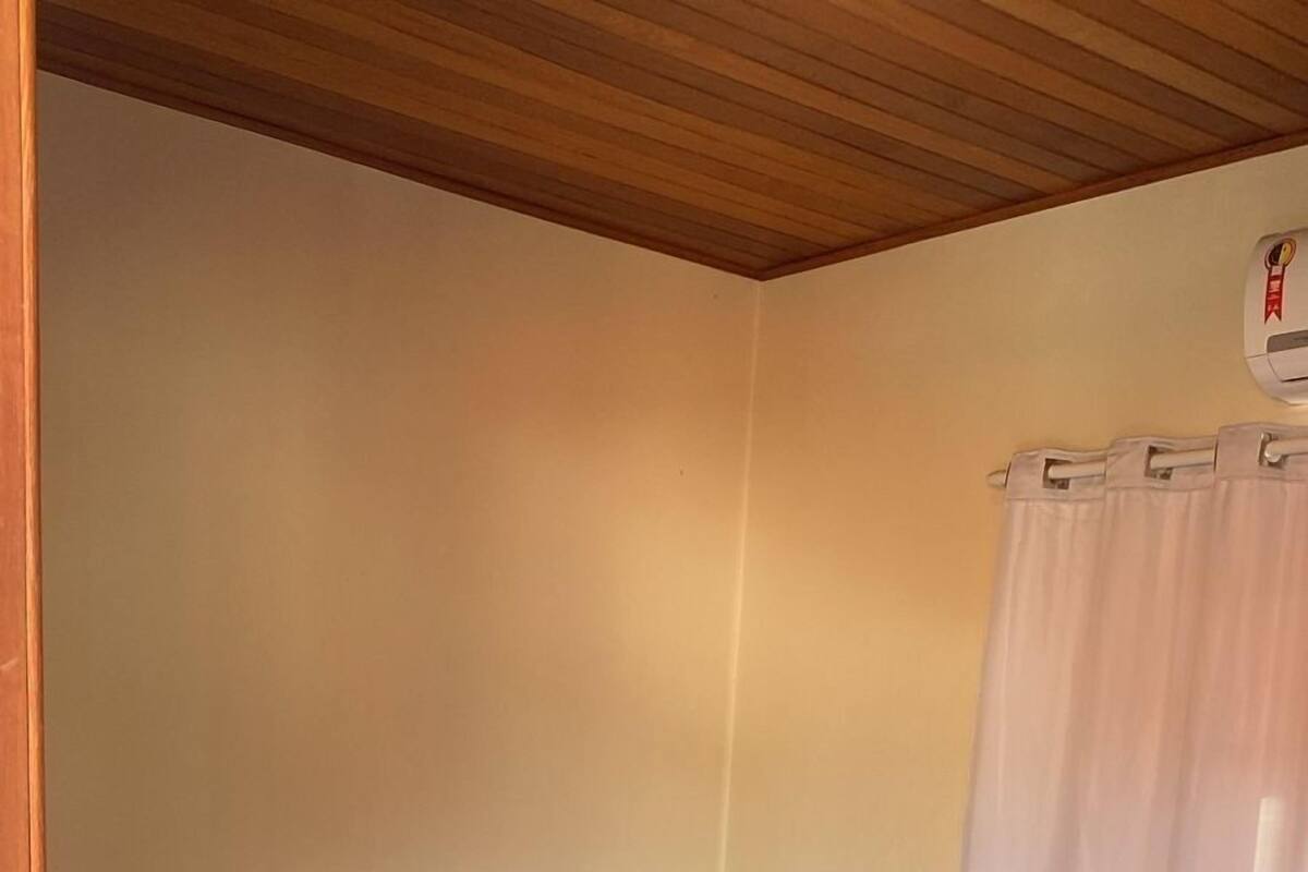 A neatly made bed with a brown headboard, a white blanket, and a folded towel on the bed.