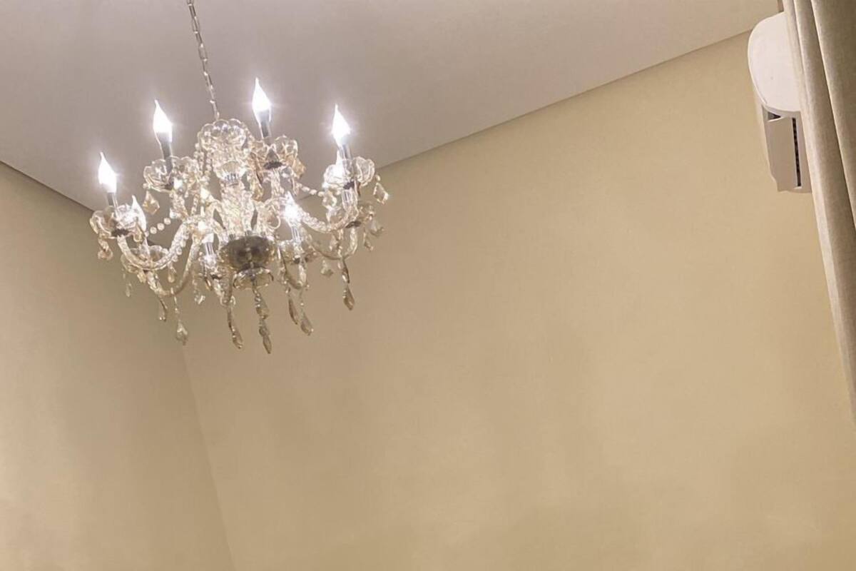A bedroom with a bed, a chandelier, and a nightstand.