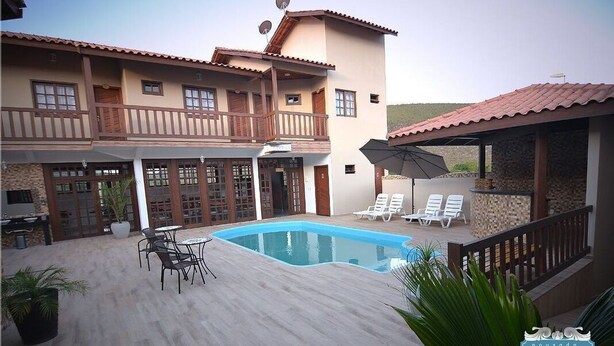 Un edificio de dos pisos con piscina, mobiliario exterior y un patio cubierto.