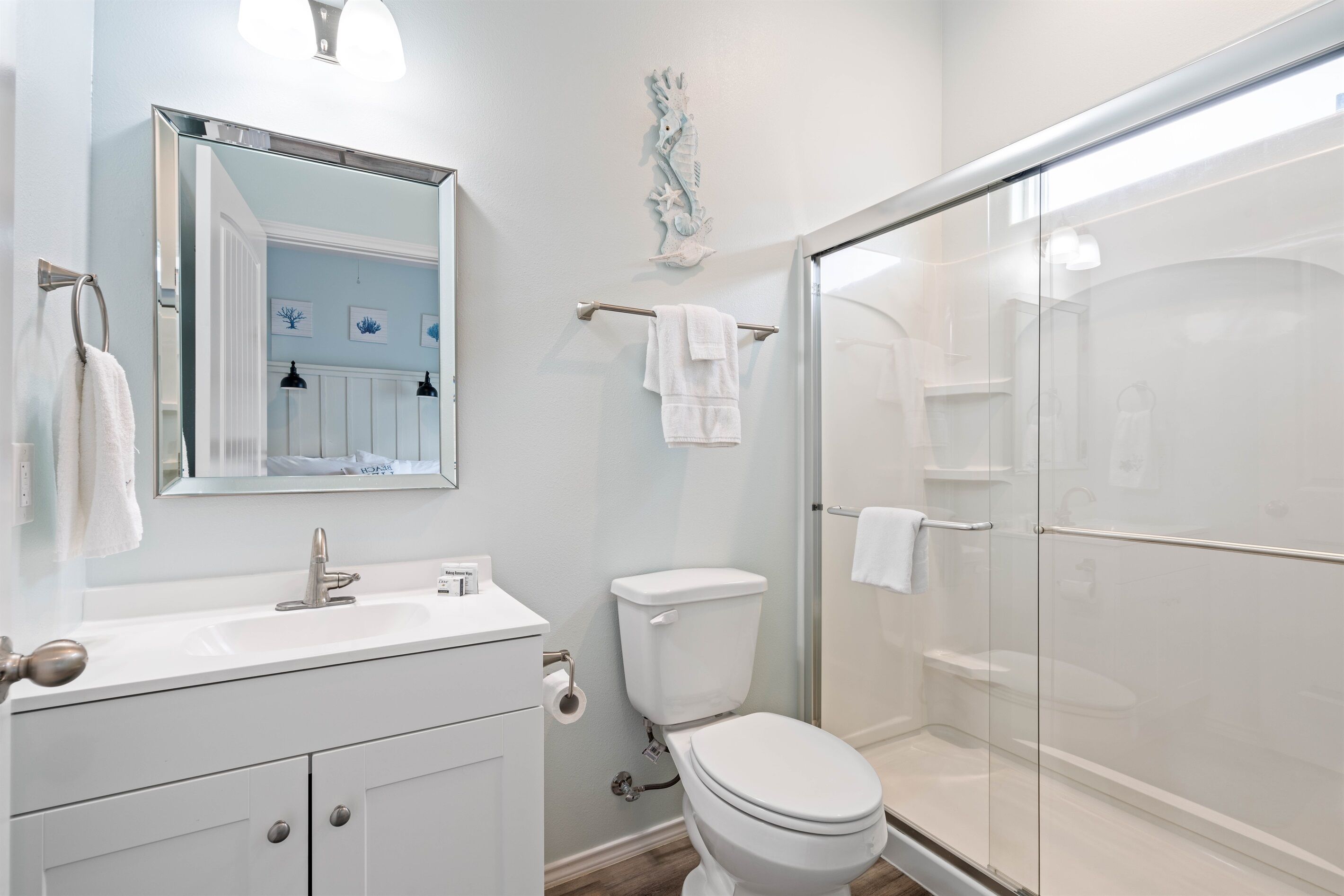 A modern bathroom with a glass shower enclosure, a white sink with a mirror, and a toilet.