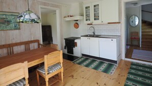 Une cuisine de taille modeste, avec des meubles blancs, une cuisinière noire et une table à manger en bois, accompagnée de chaises.