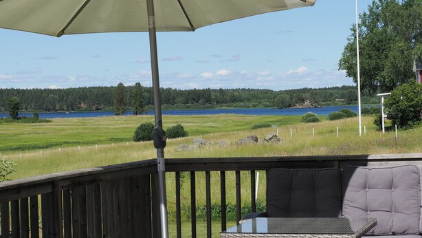 Une terrasse dotée d’une table et de chaises, offrant une vue sur un lac bordé d’une forêt.