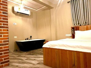 A bedroom with a wooden bed, a black bathtub, and a ceiling fan. - Charming 1-bedroom hotel in amazing Winneba with AC #3 (Winneba)