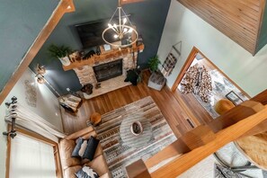 Ein modernes Wohnzimmer mit Kamin, großem Fernseher und gemütlicher Sitzecke.