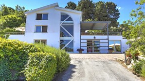 A modern two-story house with a covered driveway, large windows, and a well-maintained garden.