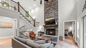 Un salón amplio con chimenea de piedra, una escalera y una zona de estar acogedora.