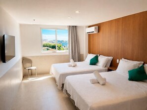 Hotelkamer met twee bedden, een televisie, een raam met uitzicht op de stad, en een airconditioning.