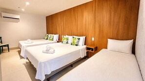 Een hotelkamer met twee bedden, een houten hoofdbord, een klein nachtkastje en een airconditioning.