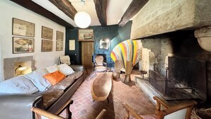 Una habitación rústica con vigas de madera a la vista, una chimenea, un sofá y una silla.