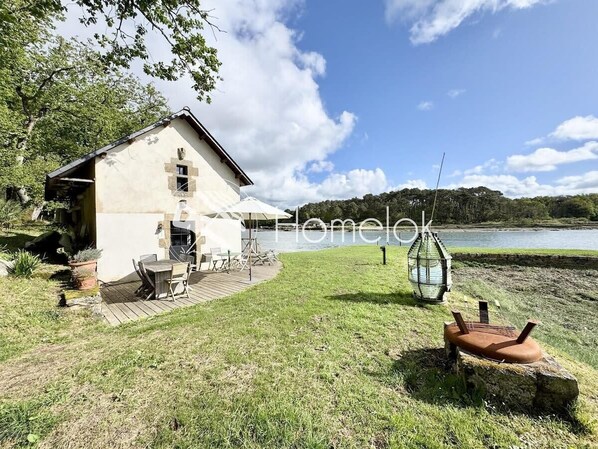 En rustik stuga med en veranda, en liten sittplats utomhus och utsikt över en sjö.
