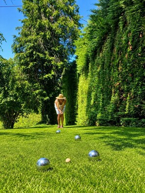 A person playing golf on a well-manicured lawn with trees in the background.