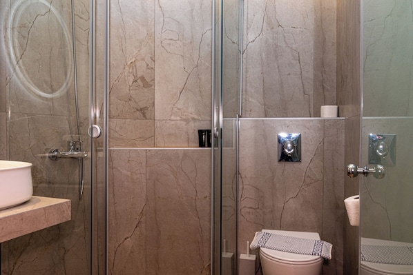 A modern bathroom with a glass-enclosed shower, a white sink, and a toilet. - Bali Seaside Sailor (Mylopotamos)
