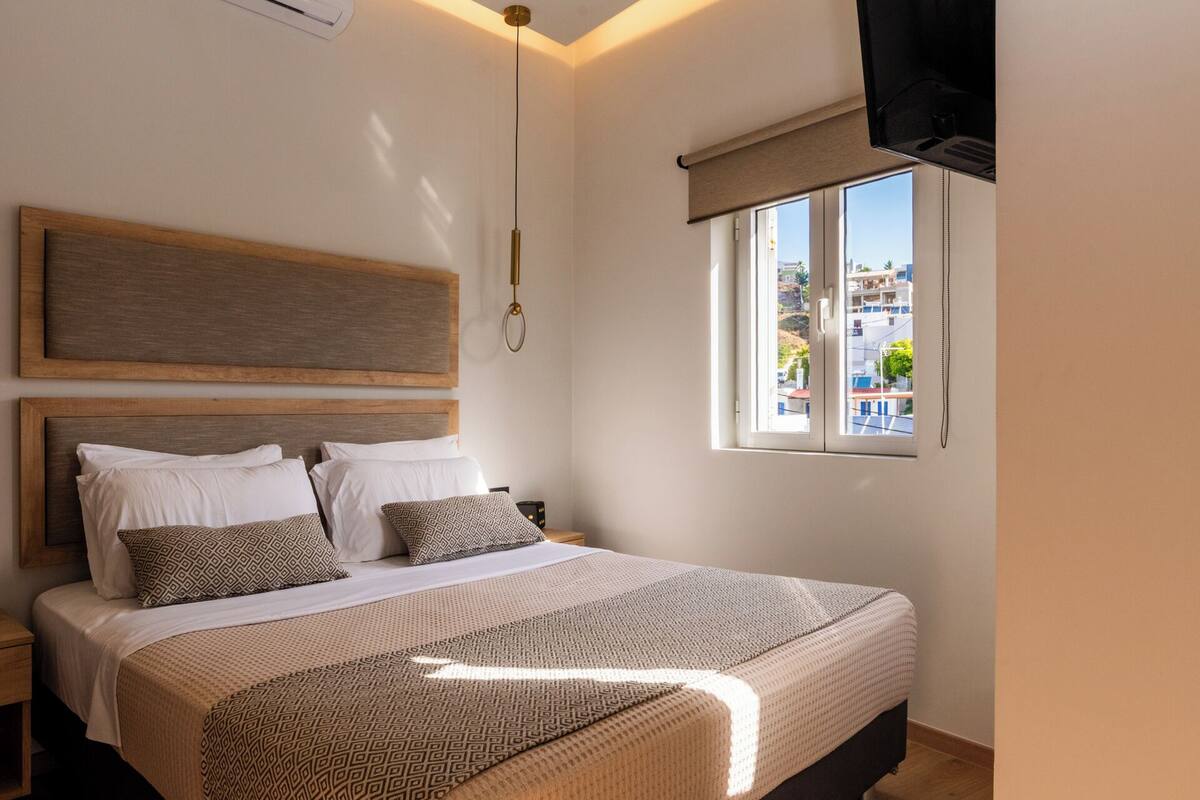 Egy hálószoba, amelyben egy nagy ágy, egy fafejű ágykeret, egy ablak, melyből kilátás nyílik az épületekre, és egy mennyezeti ventilátor található.