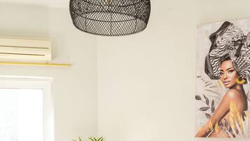 A modern bedroom with a large bed, a potted plant, and a wall-mounted lamp.