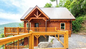 A log cabin with a wooden deck and a metal gate.