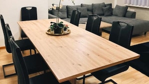 Une pièce moderne avec une table à manger en bois, des chaises noires, un canapé gris et un tableau accroché au mur.