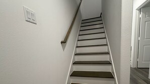 Una escalera con paredes blancas y escalones de madera.