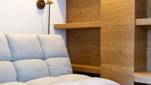 Una sala de estar moderna con un sofá de color gris claro, estanterías de madera y un aplique de pared.