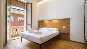 A bedroom with a bed, wooden headboard, bedside table, and a view of a brick building through a sliding glass door. - Cetra Suite a stone's throw from Santa Maria Novella (Firenze)