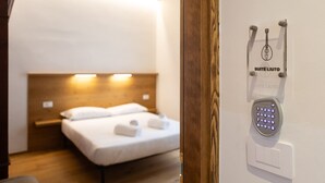 Ein Hotelzimmer mit Bett, Nachttisch und einem an der Wand montierten Schlüsselschalter für elektronische Schlüsselkarten mit der Aufschrift 'SUITE LIUTO'.