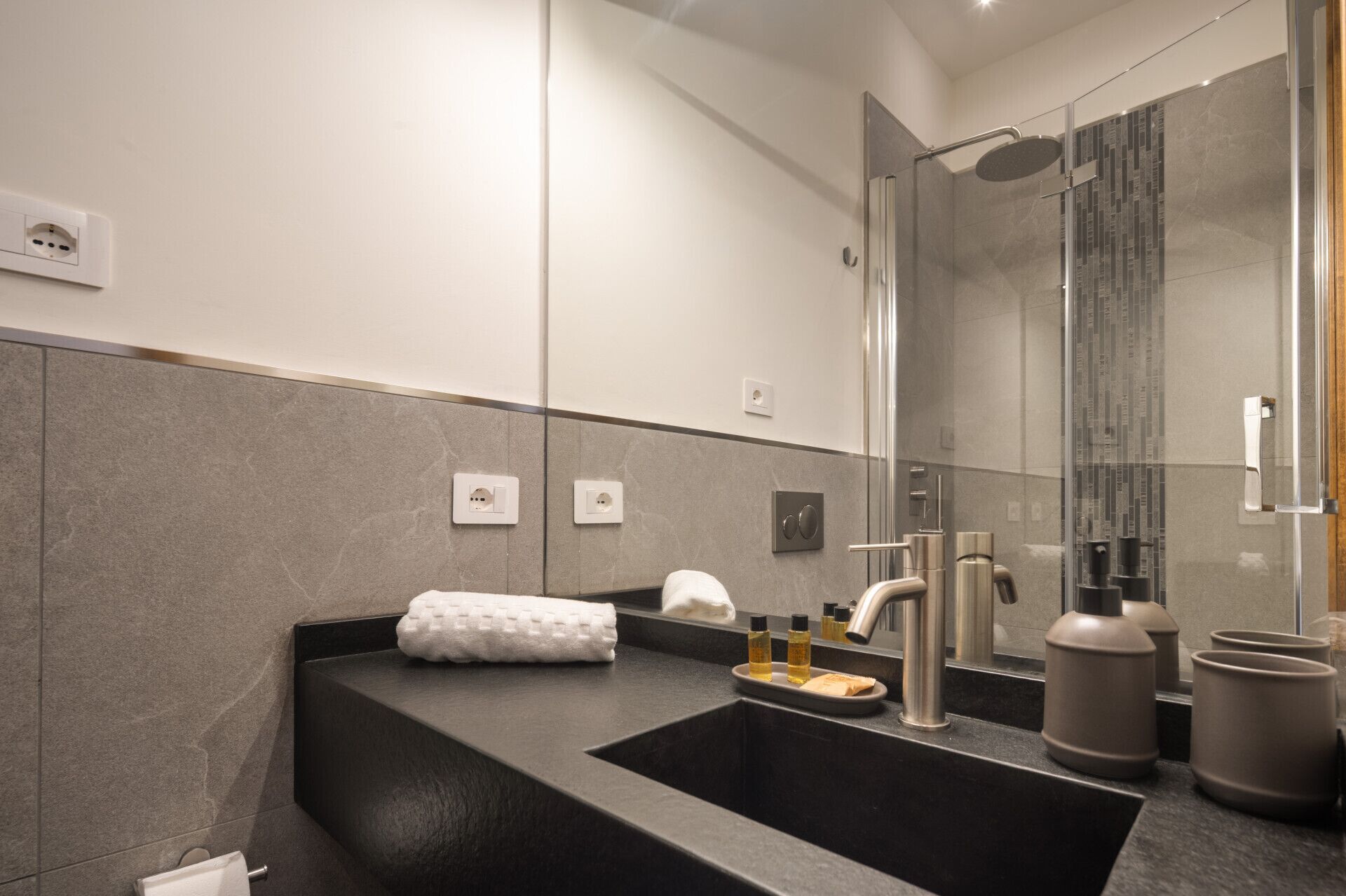 A modern bathroom with a black sink, a mirror, and a shower area.